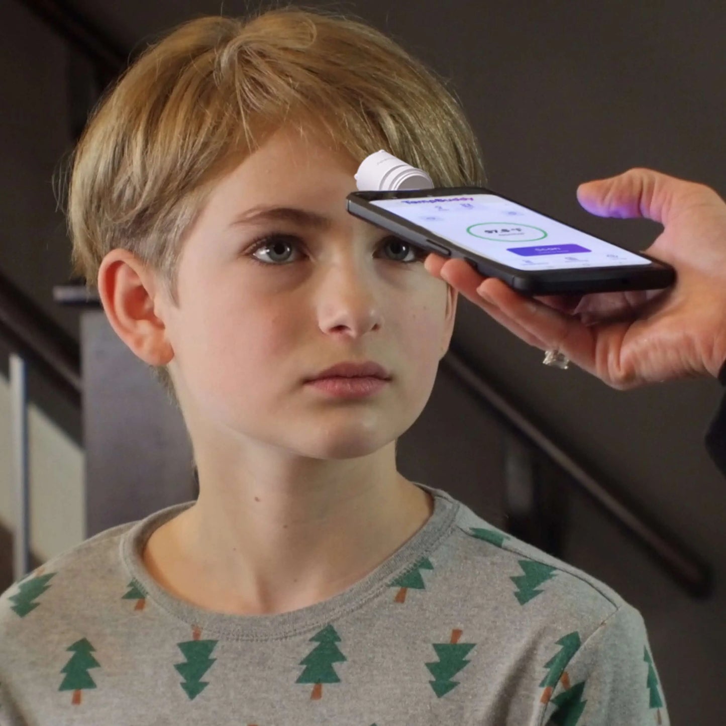 A child's temperature being checked with a TempBuddy smart thermometer with app tracking