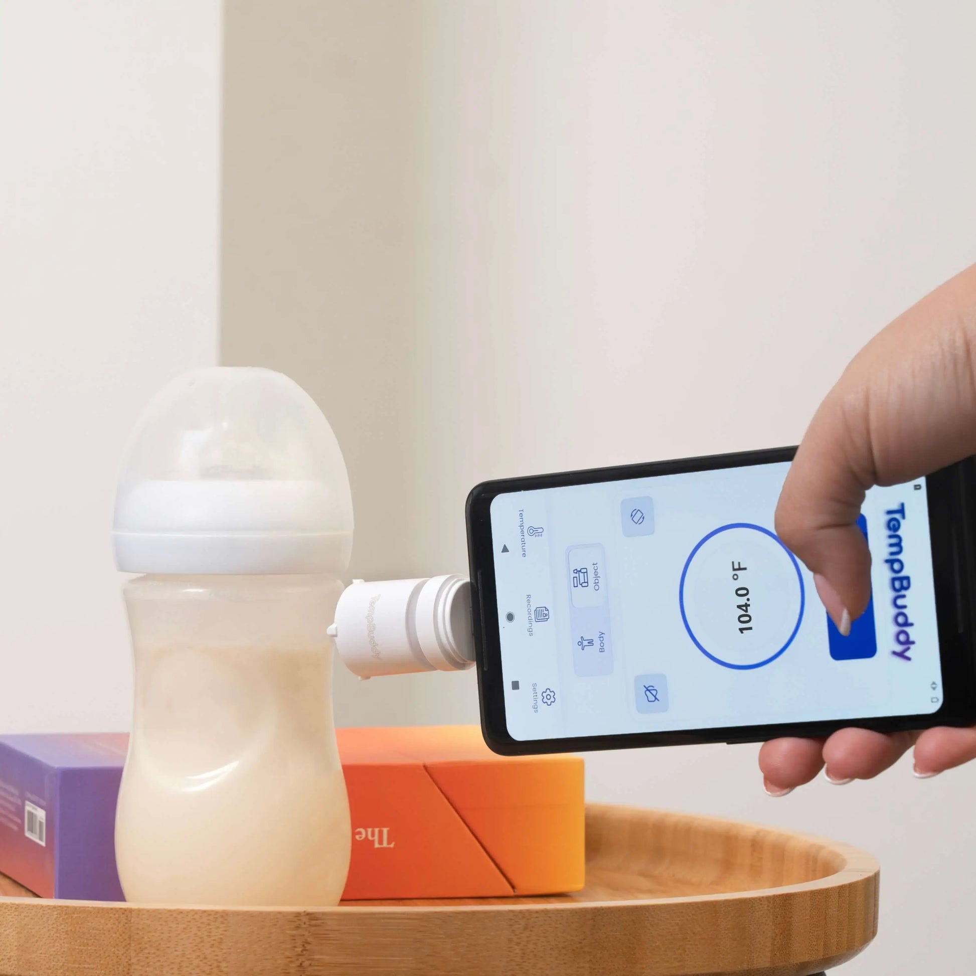 Using a smart infrared thermometer to check the temperature of a baby milk bottle for safe feeding.
