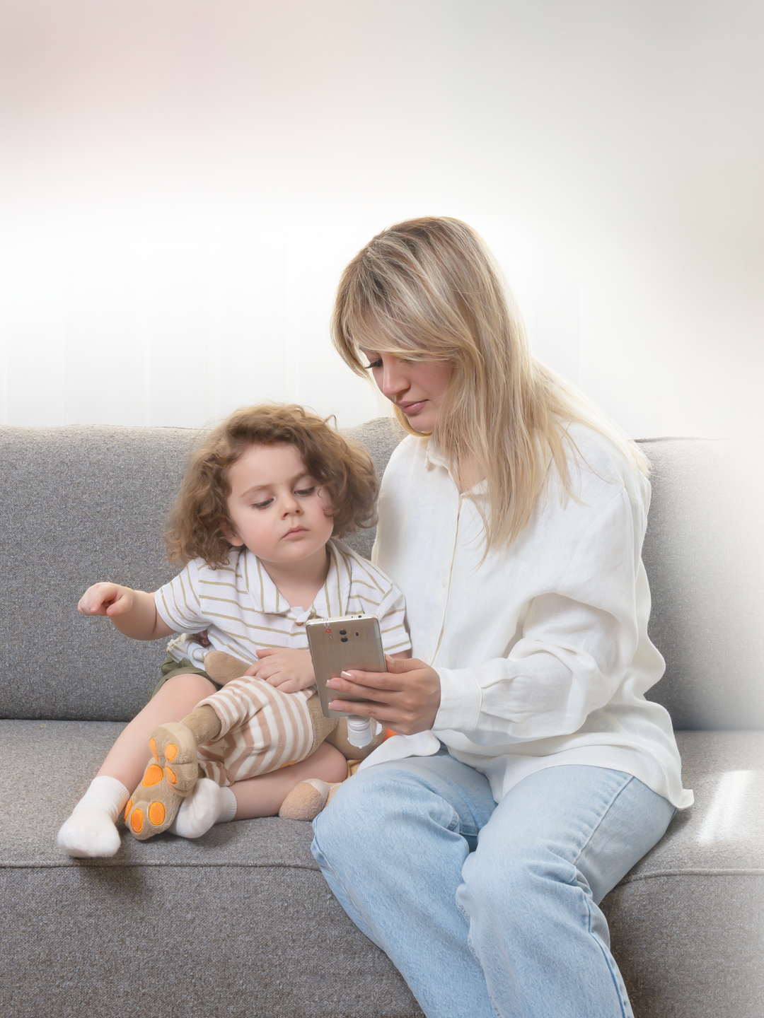 A parent and young child sitting together with a phone