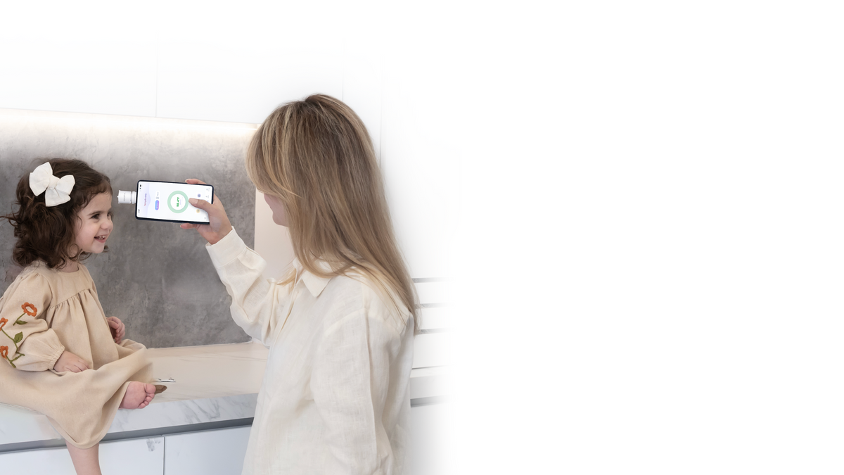 A parent scanning a child's forehead with TempBuddy plugged into a phone